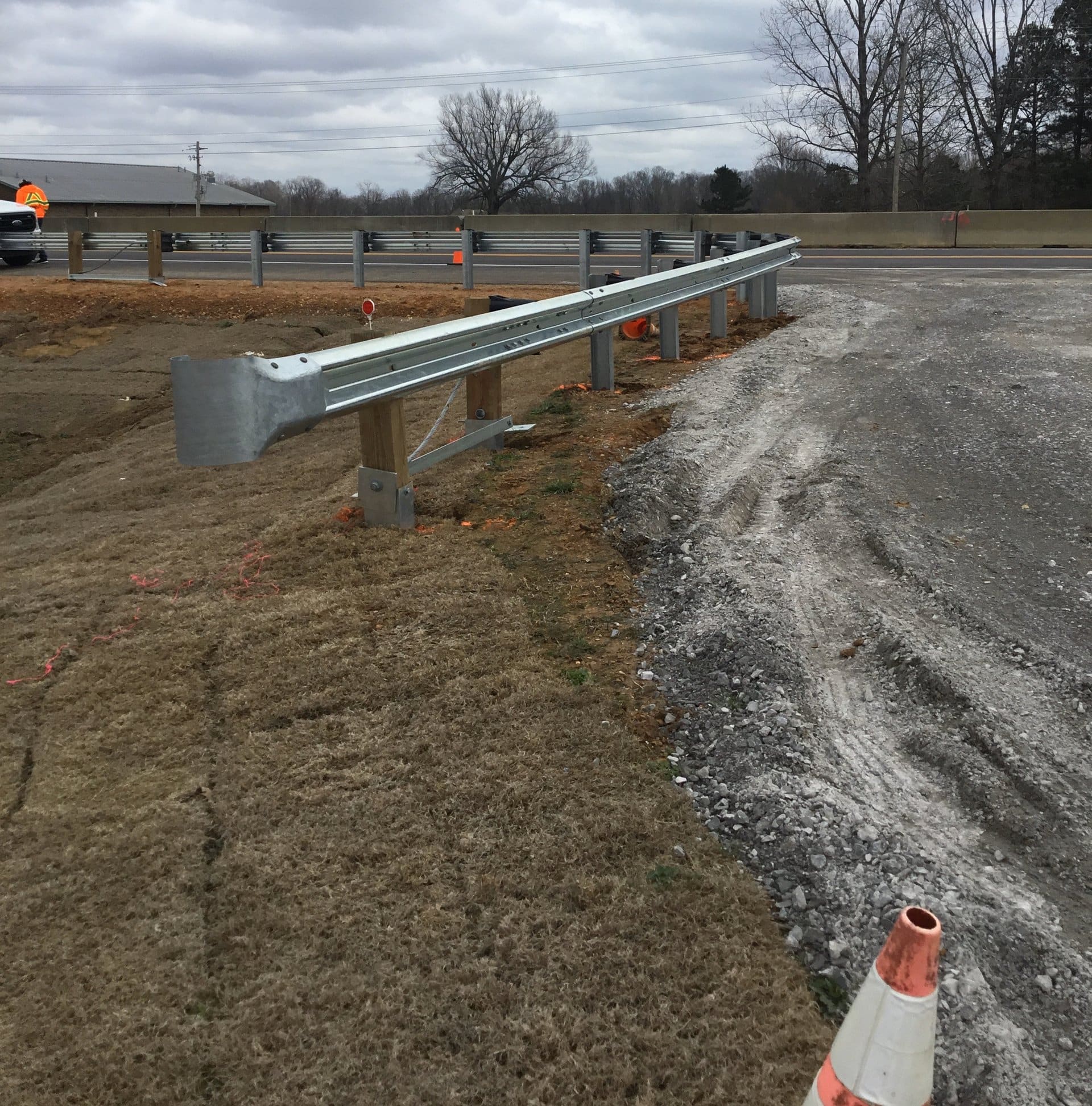New galvanized W-beam guardrail run on wood blockouts beside a highway
